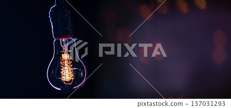A burning lamp hangs in the dark on a blurred background. Space for text. 137031293