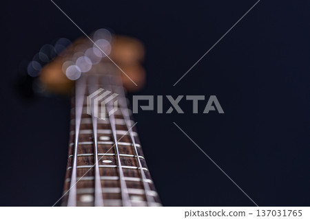 Close-up of a bass guitar fretboard on a blurred dark background. Close-up of a bass guitar fretboard on a blurred dark background. 137031765