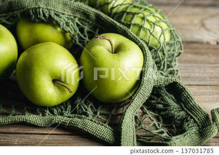Close-up, green apples in a mesh shopping bag. Close-up, green apples in a mesh shopping bag. 137031785