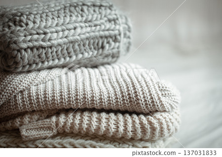 A stack of warm knitted items on blurred white background close up. A stack of warm knitted items on blurred white background close up. 137031833