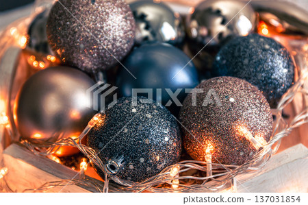Close-up, shiny Christmas balls and a garland on a wooden stand. Close-up, shiny Christmas balls and a garland on a wooden stand. 137031854