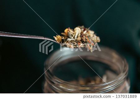 Close-up of a teaspoon and a jar of herbal tea. 137031889