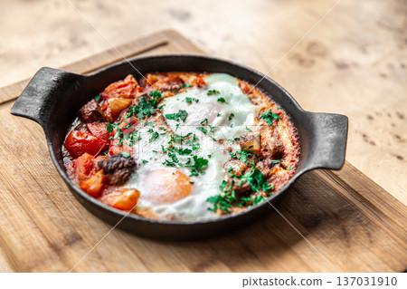 Close-up of traditional shakshuka in a frying pan on a wooden background. 137031910