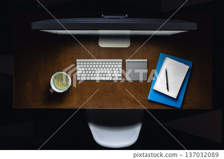 Computer, notepads and a cup of tea on the desktop at night, top view. 137032089