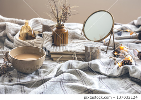 Cozy autumn composition with a cup of coffee and candles in bed. 137032124