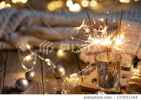 Cozy Christmas background with glowing sparklers and decor details. Cozy Christmas background with glowing sparklers and decor details. 137032164