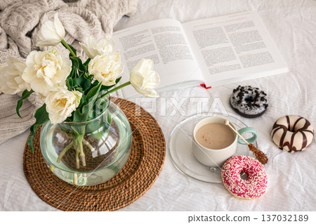 Cozy composition with a bouquet of tulips in a glass vase and a cup of coffee. 137032189