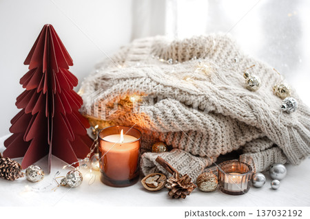 Cozy composition with burning candles, knitted element and decorative details. 137032192