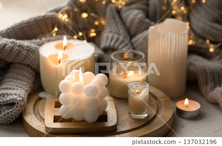 A cozy composition with candles, a knitted element and a garland. A cozy composition with candles, a knitted element and a garland. 137032196