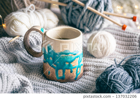Cozy composition with a cup of coffee, threads and a knitted element. Cozy composition with a cup of coffee, threads and a knitted element. 137032206