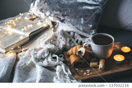 Cozy composition with a cup of tea, candles and books in bed. Cozy composition with a cup of tea, candles and books in bed. 137032216