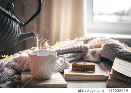 Cozy composition with a teapot, a cup and a book on a blurred background. Cozy composition with a teapot, a cup and a book on a blurred background. 137032239