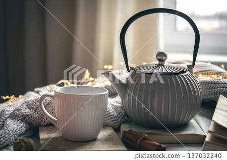 Cozy composition with a teapot, a cup and a book on a blurred background. 137032240