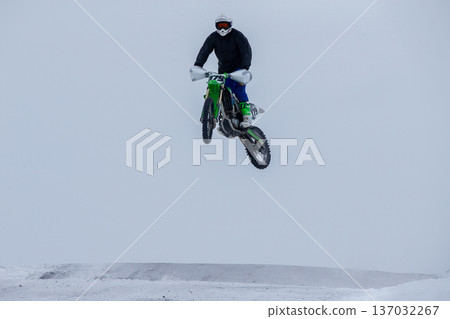 Motocross rider airborne during winter race 137032267