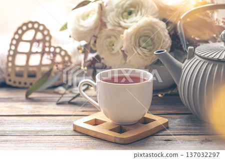 Cozy home composition with a cup of tea, teapot and flowers. Cozy home composition with a cup of tea, teapot and flowers. 137032297