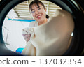 A woman putting dirty clothes into the washing machine for cleaning. household routine concept. 137032354