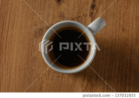A warm cup of black coffee resting on a rustic wooden table during a peaceful morning moment 137032855