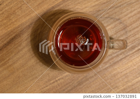 A steaming cup of aromatic tea resting on a rustic wooden table in the cozy warmth of an evening A steaming cup of aromatic tea resting on a rustic wooden table in the cozy warmth of an evening 137032891