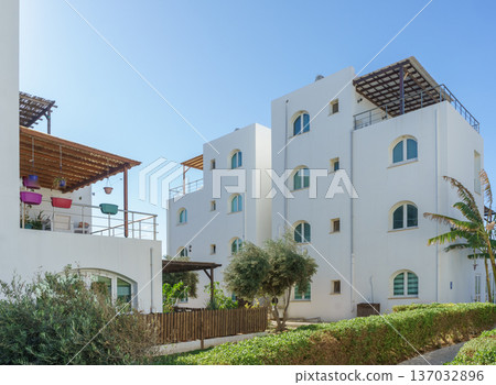 Charming white buildings nestled among greenery on a sunny day in a coastal area. 137032896