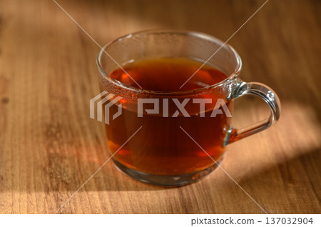 Cozy afternoon tea in a clear glass mug on a rustic wooden table inviting warmth and relaxation 137032904
