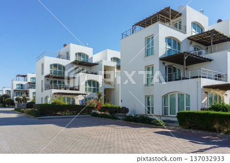 Contemporary white villas basking in sunlight near tranquil gardens on a clear 137032933