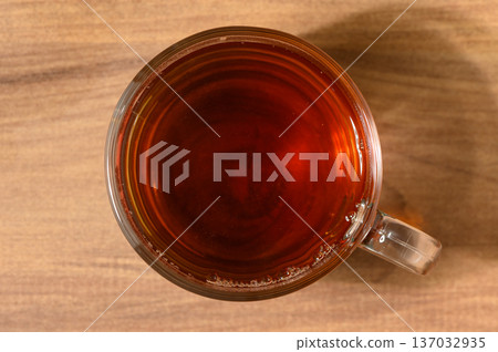 A warm cup of brewed tea resting on a wooden table in a cozy setting A warm cup of brewed tea resting on a wooden table in a cozy setting 137032935