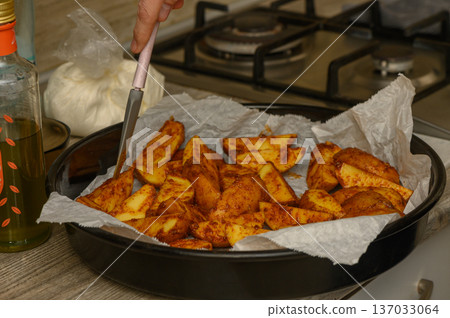 Uncooked Potato Wedges Arranged on Parchment-Lined Baking Tray 137033064