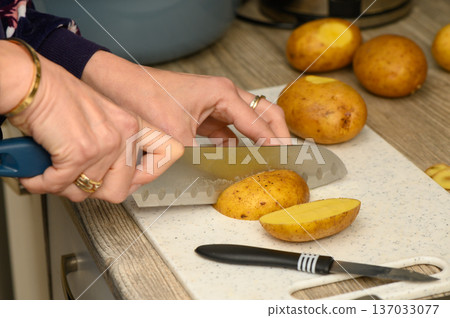Blue Handle Kitchen Knife Cutting Fresh Potatoes Close Up 137033077