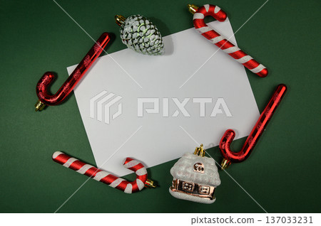 Christmas Ornaments Surrounding Empty White Note Card on Green Background Christmas Ornaments Surrounding Empty White Note Card on Green Background 137033231