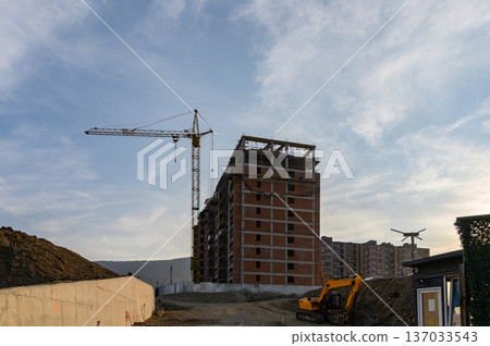 A lively city street in Tbilisi with heavy traffic flow and ongoing construction works. Tower cranes, scaffolding, and construction barriers contrast with moving cars, buses, and pedestrians. A lively city street in Tbilisi with heavy traffic flow and ongoing construction works. Tower cranes, scaffolding, and construction barriers contrast with moving cars, buses, and pedestrians. 137033543