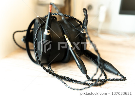 Black monitor headphones on a table with audiophile wires, representing high-quality music listening. Professional audio equipment for studio monitoring, critical listening, and immersive sound  137033631