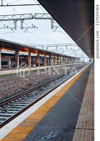 Train station platform with empty tracks during early morning hours in a city 137034364