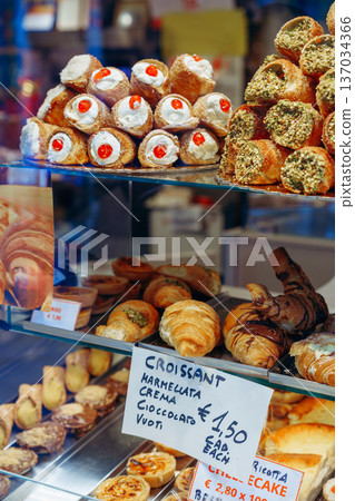Bakery display with many types of pastries and cakes in a shop window Bakery display with many types of pastries and cakes in a shop window 137034366