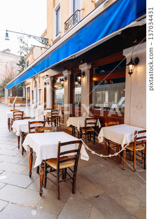 Outdoor cafe seating with tables and chairs on a quiet street in the daytime Outdoor cafe seating with tables and chairs on a quiet street in the daytime 137034431