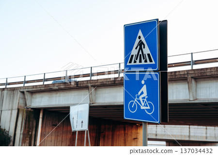 Traffic signs show pedestrian and bicycle paths near a highway overpass in the city Traffic signs show pedestrian and bicycle paths near a highway overpass in the city 137034432