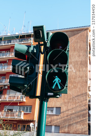 Green pedestrian signal shows person icon on busy street in city during bright day Green pedestrian signal shows person icon on busy street in city during bright day 137034450