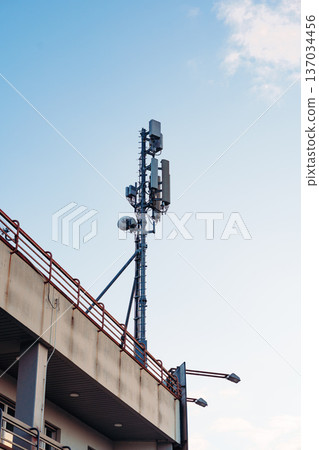 Cell tower stands on a building under a clear sky in a city during daytime Cell tower stands on a building under a clear sky in a city during daytime 137034456