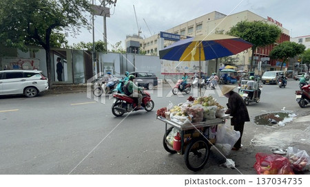 A motorbike and a street vendor wearing a hat on a road in Ho Chi Minh City, Vietnam 137034735