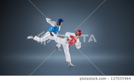 Professional taekwondo fighters in dynamic kick exchange on blue background wearing protective helmets and chest guards. Professional taekwondo fighters in dynamic kick exchange on blue background wearing protective helmets and chest guards. 137035464