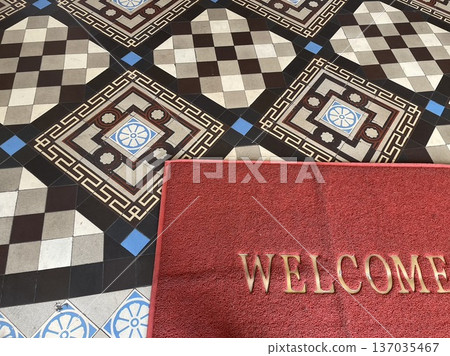 Beautiful tile floor and red mat with "WELCOME" written on it 137035467