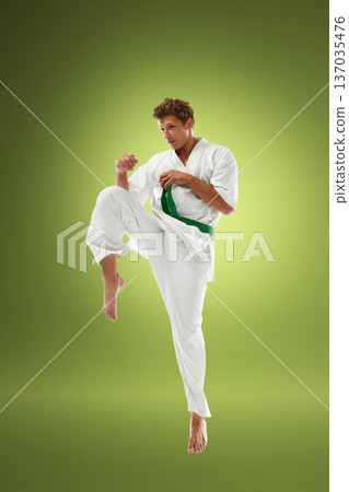 Young karate fighter practicing knee lift guard position in white gi with green belt 137035476
