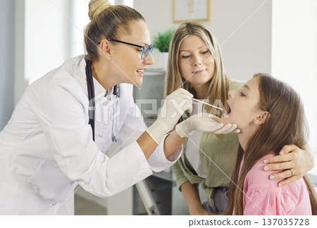 Pediatrician taking throat swab from child patient as mother supports in clinic Pediatrician taking throat swab from child patient as mother supports in clinic 137035728