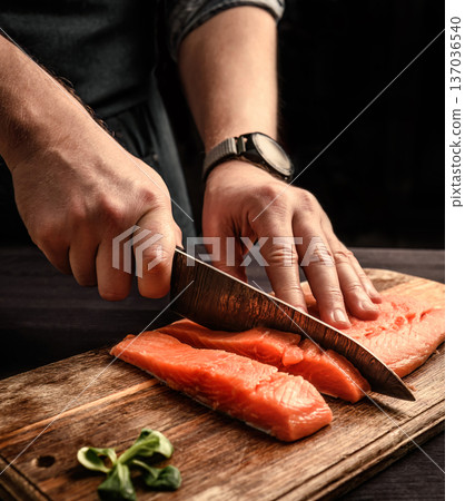 chief cutting a salmon fillet into pieces for cooking chief cutting a salmon fillet into pieces for cooking 137036540