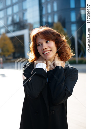 Joyful Beautiful Businesswoman Smiling And Touching Neck Outdoors Joyful Beautiful Businesswoman Smiling And Touching Neck Outdoors 137036607