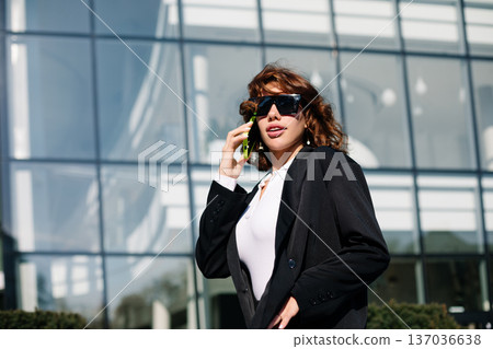 Stylish businesswoman posing with smartphone in modern architecture setting Stylish businesswoman posing with smartphone in modern architecture setting 137036638