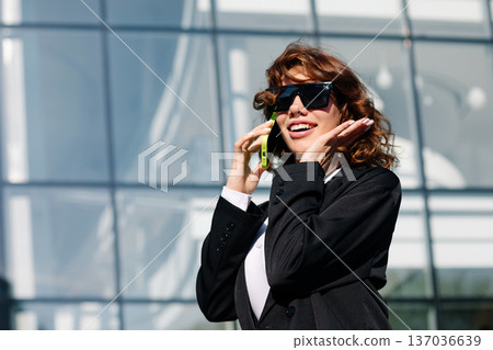 Confident businesswoman making gesture while talking on smartphone outdoors 137036639