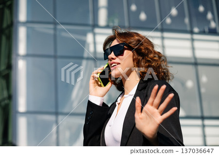 Businesswoman Walking And Talking On Phone In Modern City Street Businesswoman Walking And Talking On Phone In Modern City Street 137036647