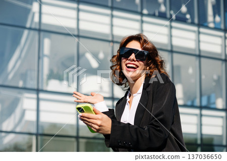 Smiling Businesswoman Talking On Phone Near Glass Building Smiling Businesswoman Talking On Phone Near Glass Building 137036650