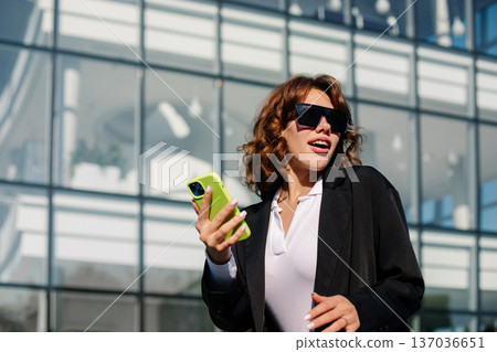 Confident Businesswoman Using Smartphone Outdoors In Corporate Setting 137036651