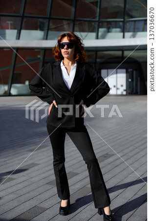 Confident Businesswoman Standing With Hands On Hips Near Office Building Confident Businesswoman Standing With Hands On Hips Near Office Building 137036670